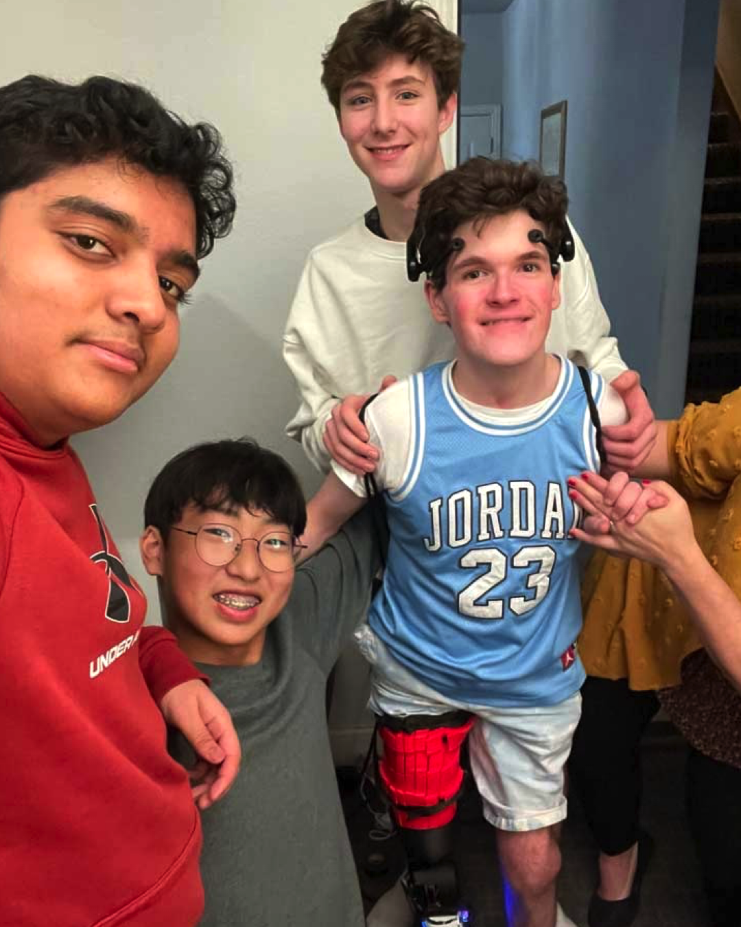 From left to right: Prashanth, Kim, and Skotnikov smile with their friend, Aiden, in his new NeuroFlex.